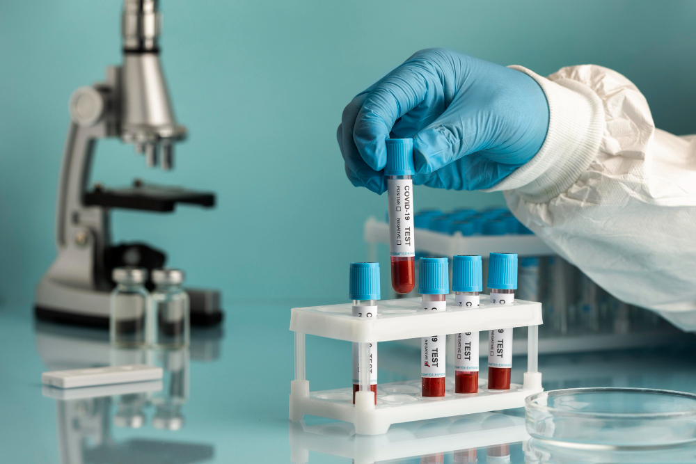 Gloved hand holding a blood sample beside a microscope